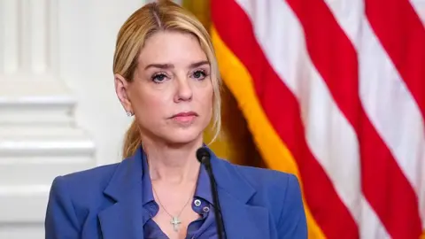 Bloomberg via Getty Images close-up of Pam Bondi, wearing blue suit, looking serious in front of a microphone