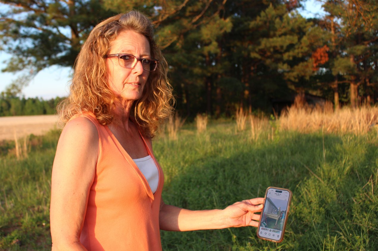 A woman holds up her phone, showing work being done on a mobile home.
