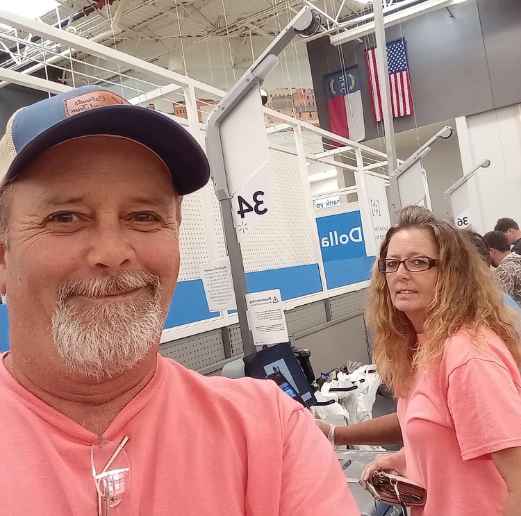 A man takes a selfie, smiling. His sister is behind him.