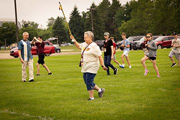Grandparents and grandchildren march across a field like members of a marching band