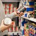 Stock image of a woman holding tins in the supermarket aisle.