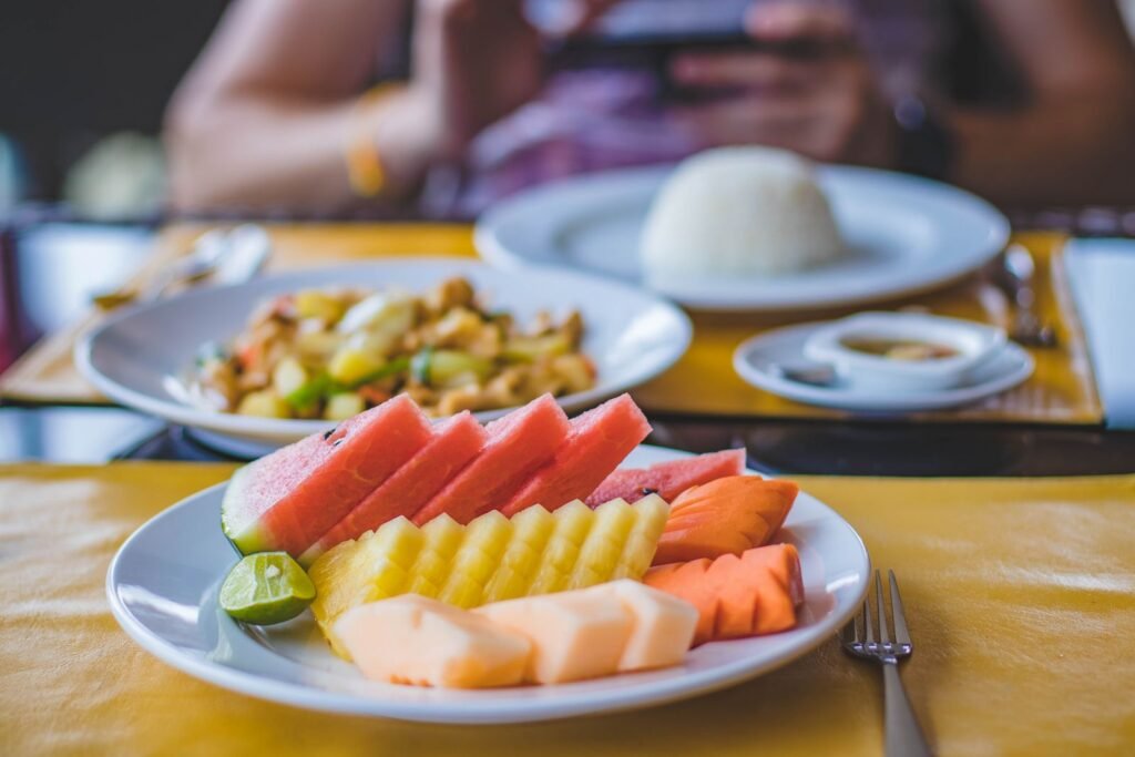 Vibrant and appetizing fruit platter served with a traditional Asian meal on a well-set dining table.