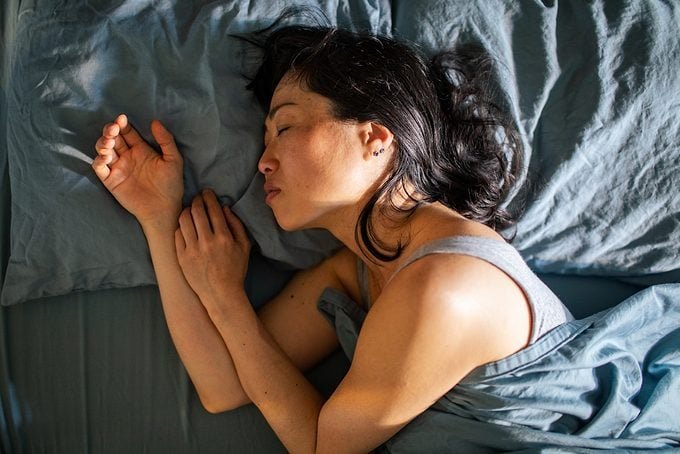 Young Japanese woman sleeping in a bed in a bedroom