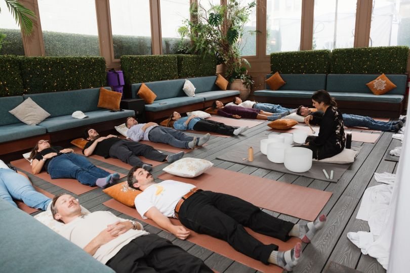 Several Riskified team members lie on yoga mats during a sound bowl healing session at a “Riski-reset” offsite day centered around wellness.