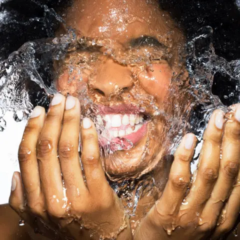 Getty Images Young female splashing face with water