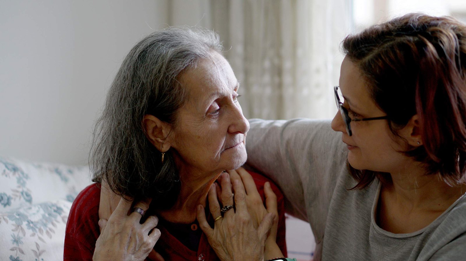 An older man looks pensive while a woman comforts him by placing her hand on his shoulder.