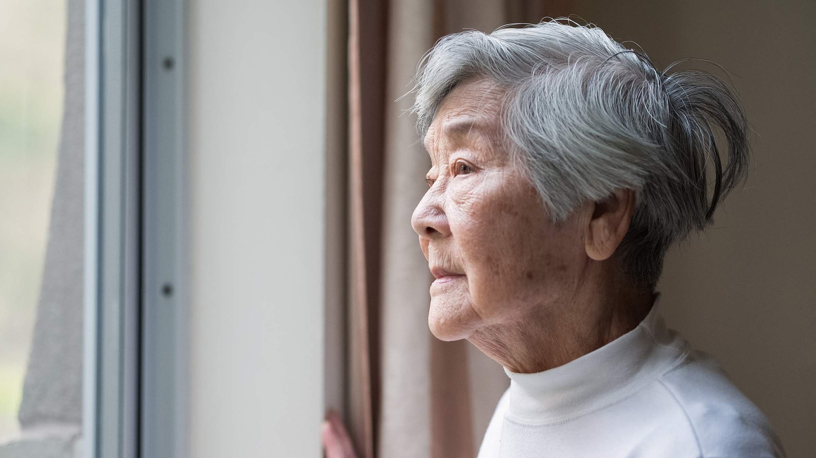 older woman looking outside window