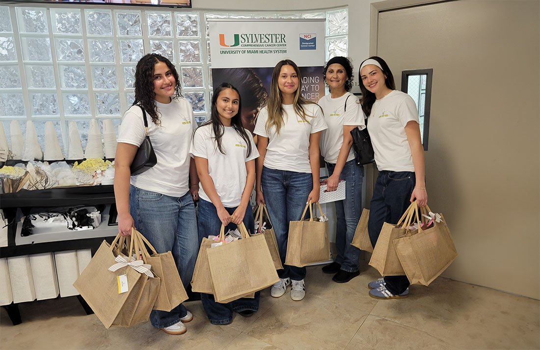 Group holding tote bags filled with care packages from the “More for Mom” initiative at Sylvester Comprehensive Cancer Center, University of Miami Health System.