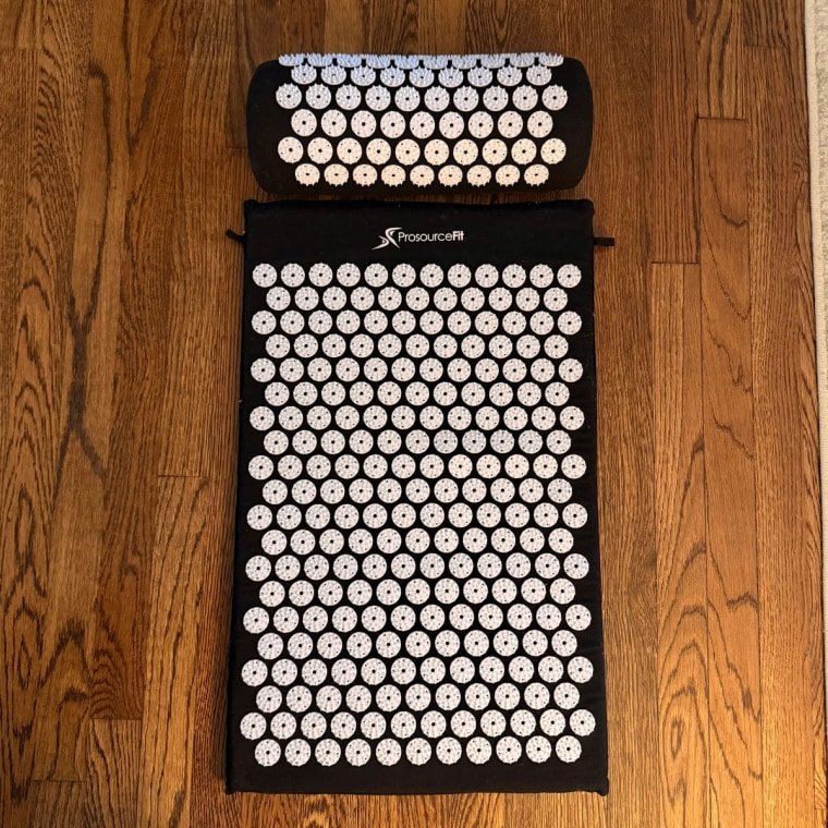 ProsourceFit’s Acupressure Mat and Pillow Set on a wood floor.