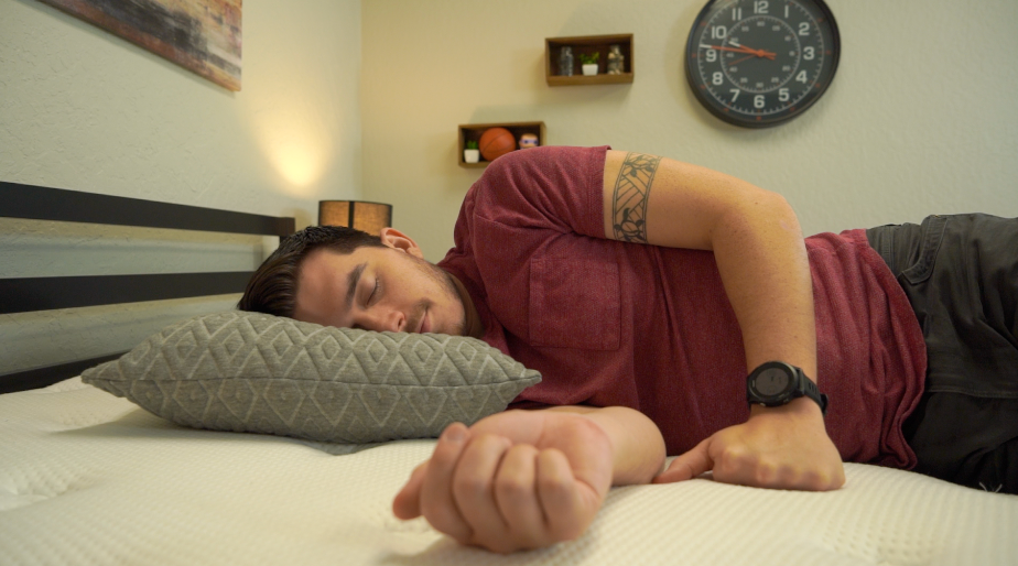 man in red t-shirt sleeping on his side on a gray pillow