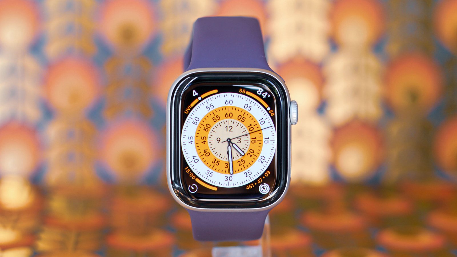 An Apple Watch Series 11 with purple band on a blurred, colorful background.