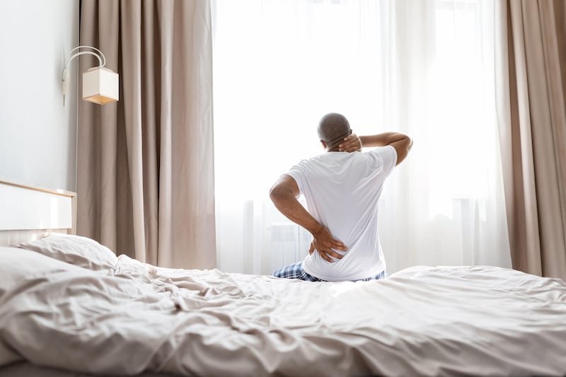 This is a generic photo of a man sitting on a bed holding his neck and back in discomfort. See PA Feature WELLBEING Sleep. WARNING: This picture must only be used to accompany PA Feature WELLBEING Sleep. PA Photo. Photo credit should read: Alamy/PANOTE TO EDITORS: This picture must only be used to accompany PA Feature WELLBEING Sleep