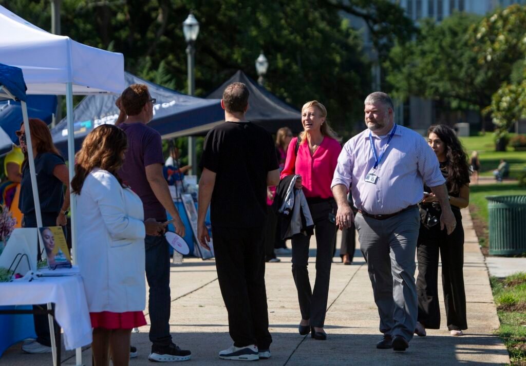 Dr. Griffin and Dr. Sean Troxclair, her deputy, walk down a sidewalk lined with tented displays at a women’s wellness event near the State Capitol in May.