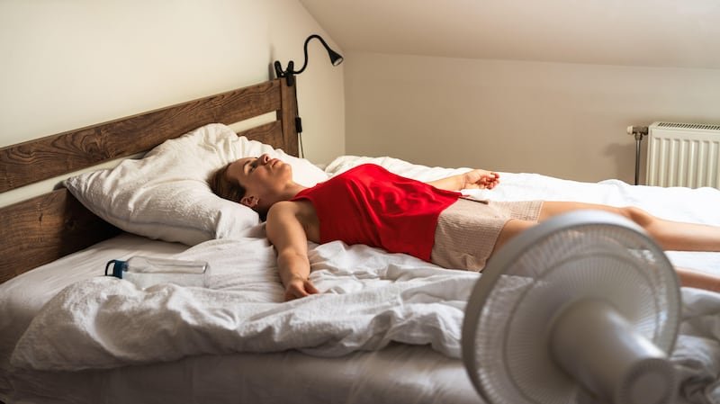 This is a generic photo of a young woman lying in bed next to a fan. See PA Feature WELLBEING Sleep. WARNING: This picture must only be used to accompany PA Feature WELLBEING Sleep. PA Photo. Photo credit should read: Alamy/PANOTE TO EDITORS: This picture must only be used to accompany PA Feature WELLBEING Sleep