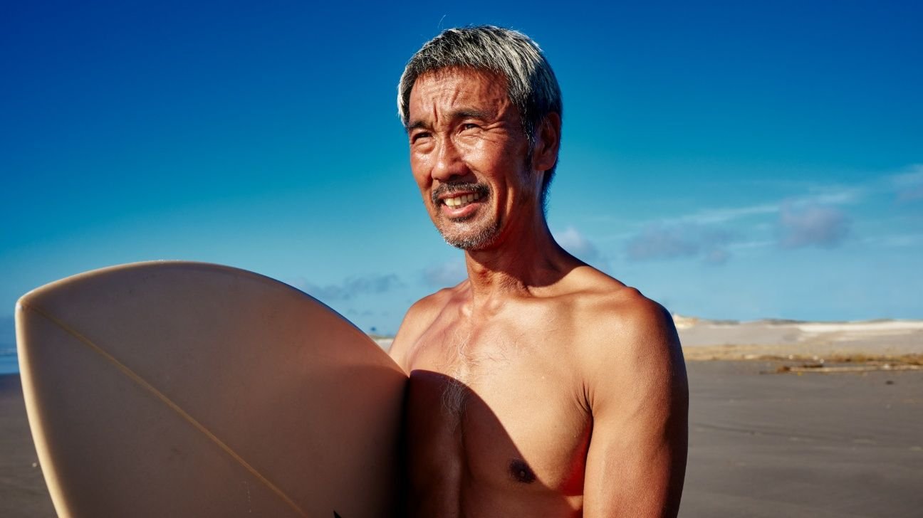 Older male with surfboard at beach