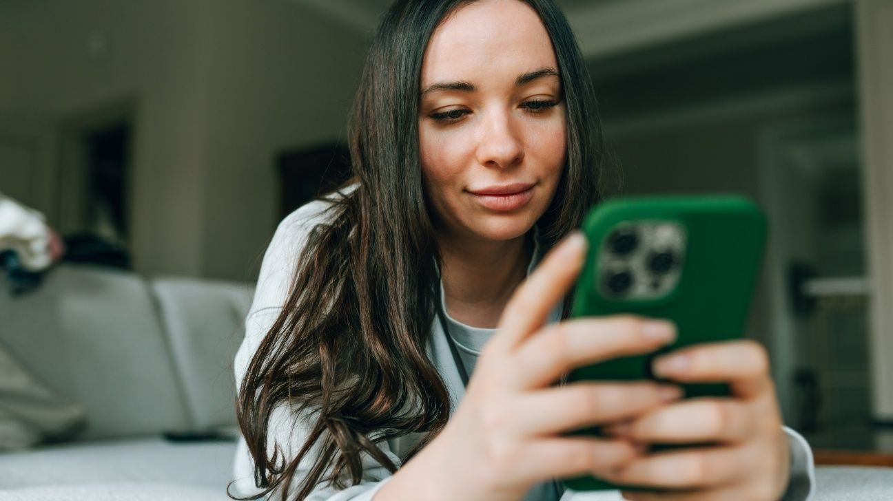 Female lying on a sofa and using her smartphone