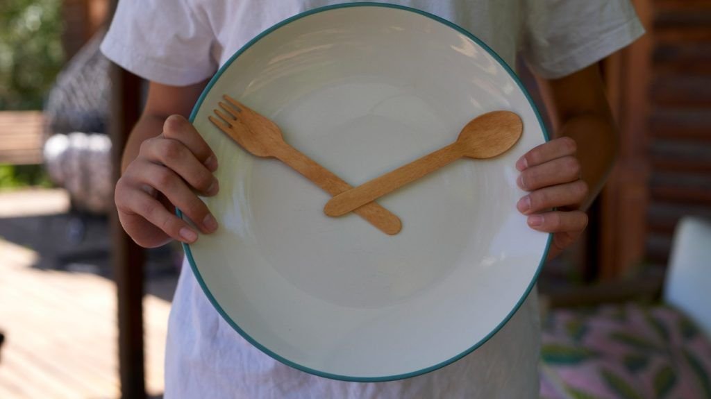 A person is holding a plate designed to look like a clock face.