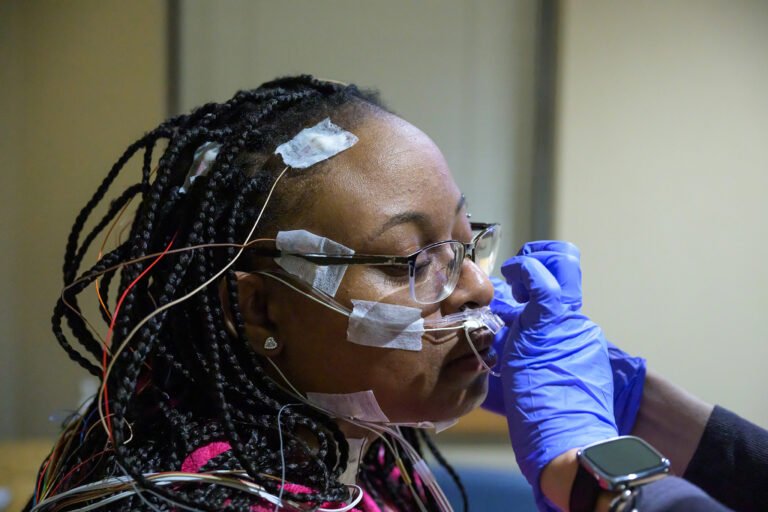 Patient with electrodes taped to her face and head securing a clear nasal cannula.