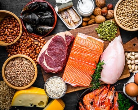 Overhead view of a large group of food with high content of healthy proteins. The composition includes salmon beef fillet, chicken breast, eggs, yogurt, mussels, chick peas, pistachios, cheese, brown lentild, beans, shrimps, canned tuna, pumpkin seeds, soybeans among others.