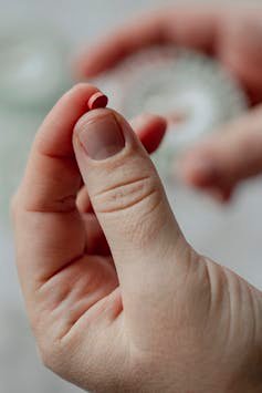 Close-up of hand holding a small round pill