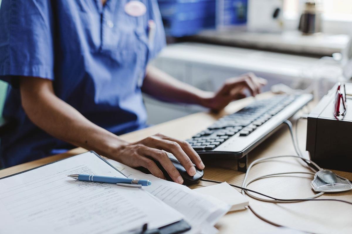 Health care worker using computer at desk in hospital