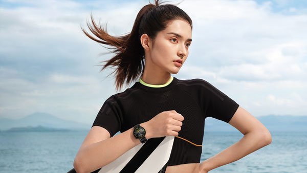 Woman doing a stretching routine near the water while using a fitness wearable.
