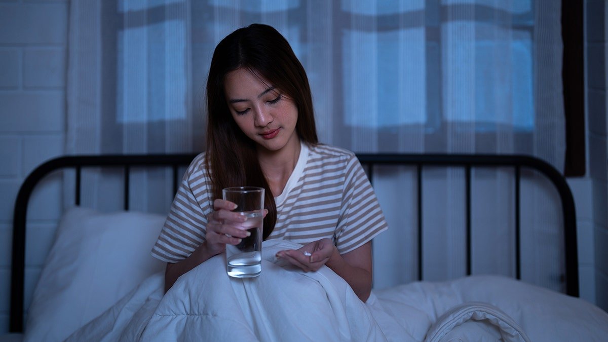 girl with pills and glass of water in bed
