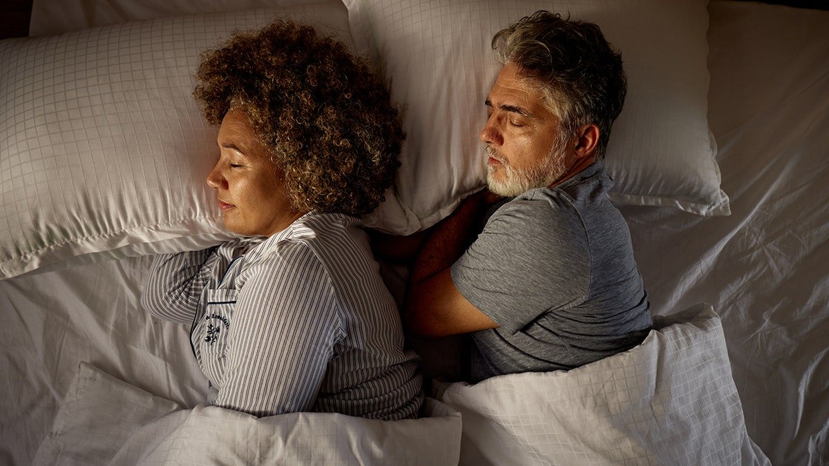 Overhead shot of relaxed couple sleeping soundly in a bed.