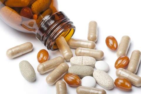 brown medicine bottle spilling beige tablets and amber softgels