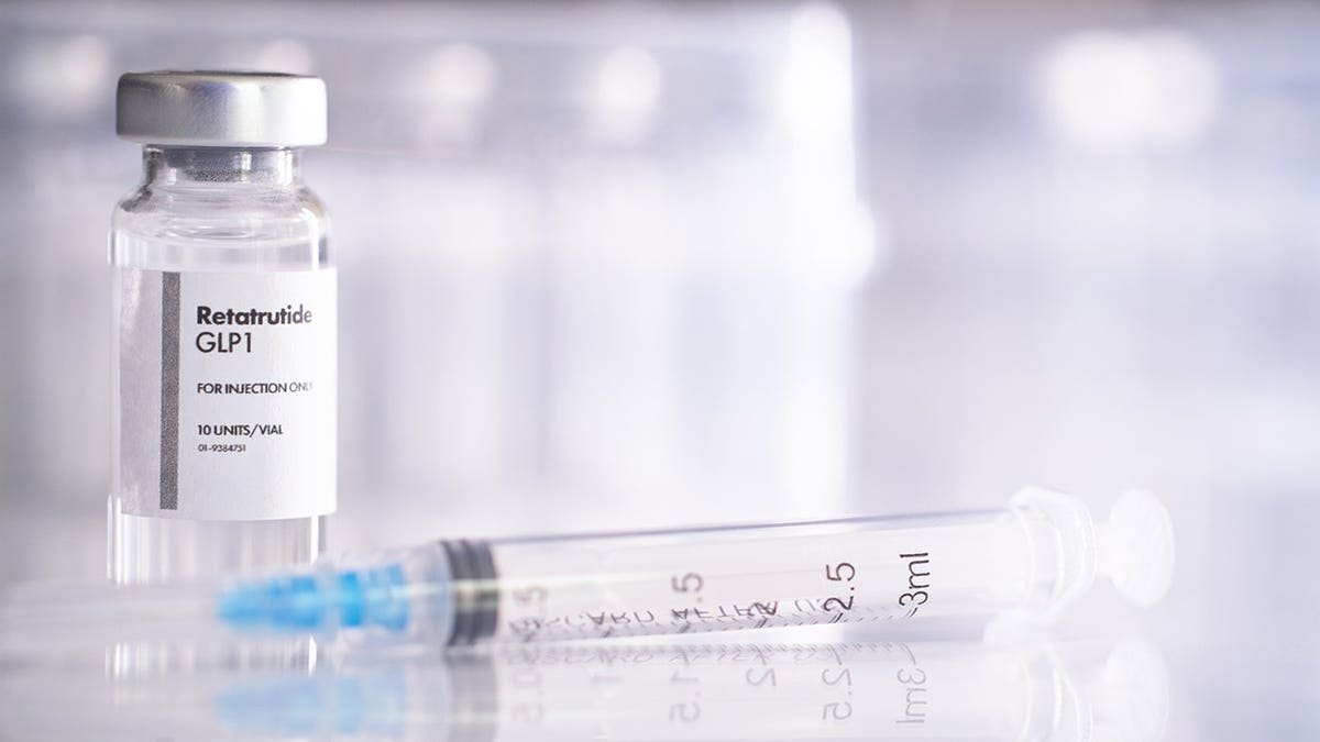 A vaccine vial and syringe containing GLP-1 peptide retatrutide on a surface.